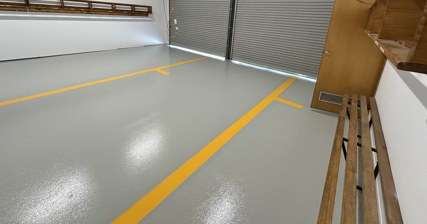 Grey commercial epoxy floor with yellow line-marking in a warehouse